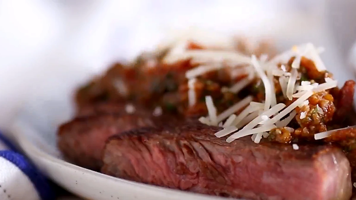 Sliced steak topped with mushroom marinara and grated parmesan