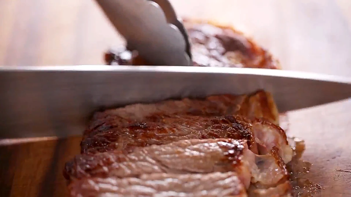 A rested steak being sliced against the grain