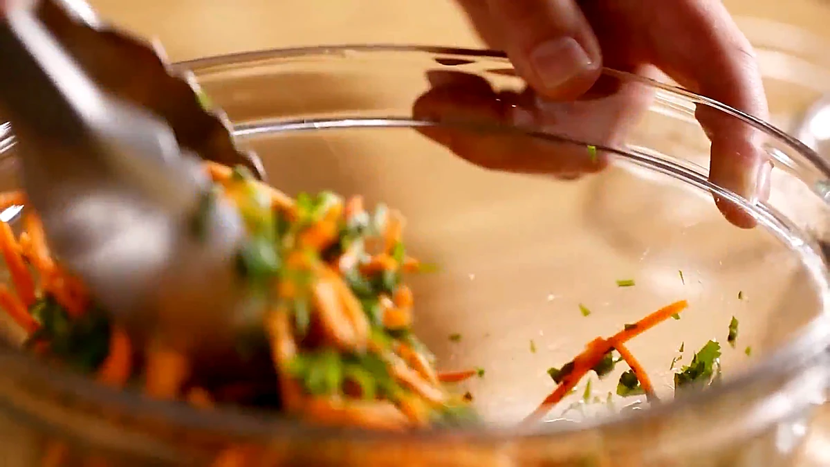 Carrot basil salad tossed in a glass bowl