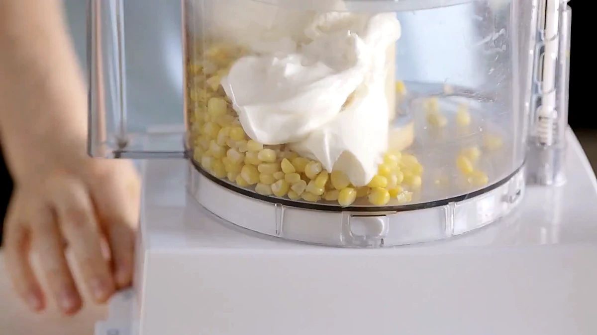 Corn and ricotta cheese being blended in a food processor