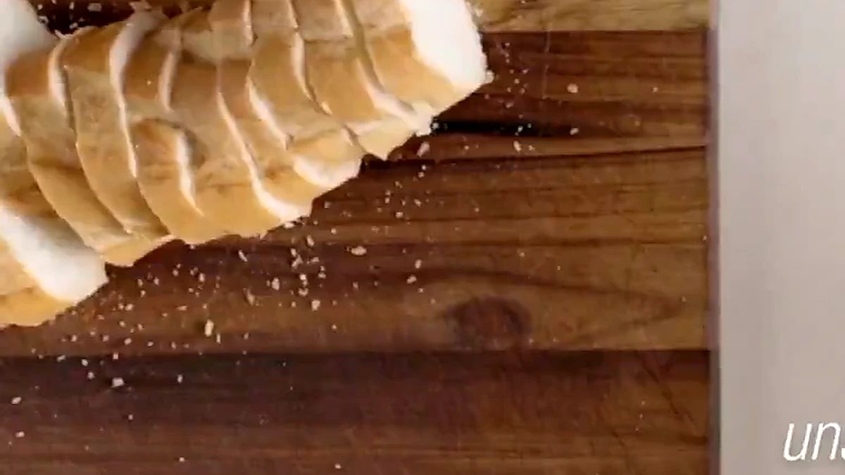 Baguette being sliced into thick rounds on a cutting board