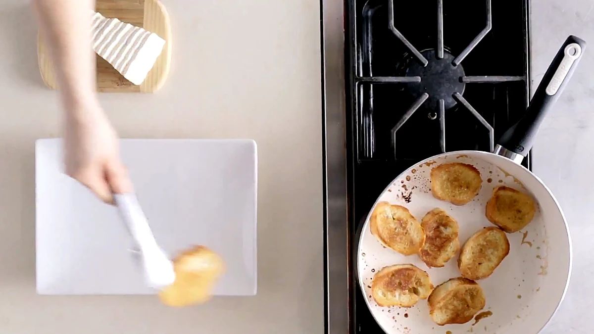 Golden toasted bread slices moved onto a board