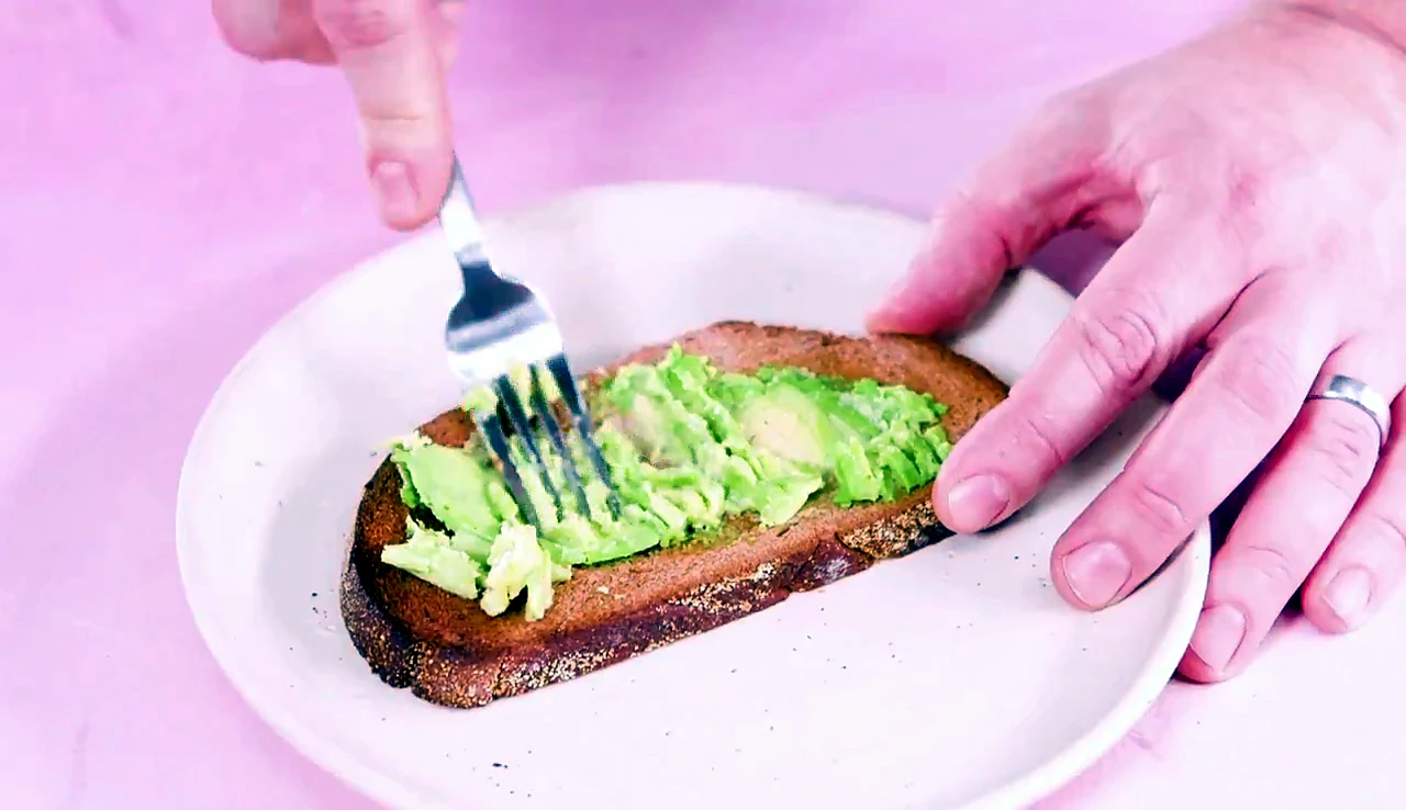 Avocado mashed over toast with a fork
