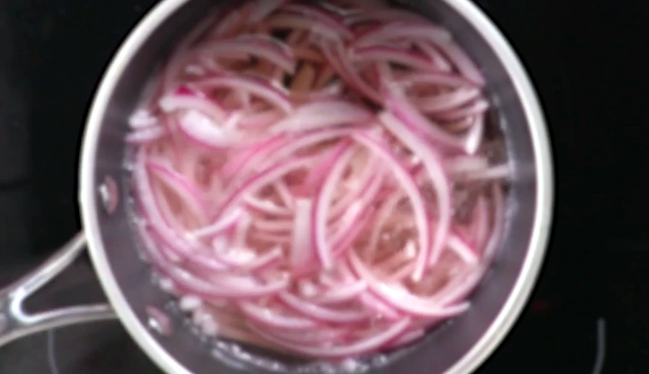 Pink quick pickled red onions in a pan